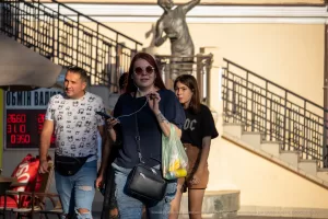 Фото тату на руке женщины: небольшой рисунок, возможно, цветок или абстрактный узор. Женщина стоит на улице.