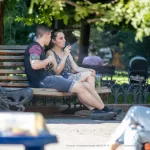 Фото тату: Молодой человек с татуировками на руках сидит на скамейке рядом с девушкой. Татуировки изображают яркие и красочные рисунки.