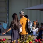 Фото тату на руке и шее мужчины, идущего по улице с девушкой. Видны детализированные рисунки татуировок в стиле традишнл.