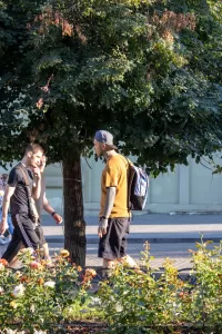 Фото тату на руках мужчины, идущего по улице. Видны детализированные рисунки в стиле традишнл и графика.