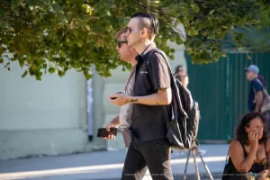 Фото тату: черно-серый рисунок кота, окруженного цветами, на руке мужчины. Детализированный эскиз тату с использованием теней и градиентов.
