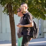 Фото тату: небольшой черный рисунок кота на руке мужчины, выполненный в минималистичном стиле. Изящный эскиз тату для любителей животных.