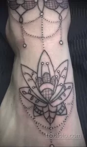 Фото тату: черная контурная татуировка цветка лотоса на женском боку, выполненная в стиле кружева.