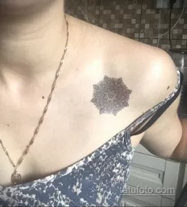 Фото тату: круглая татуировка в виде мандалы, расположенная на ключице, выполнена в технике дотворк с использованием множества мелких точек.