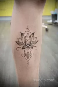 Фото тату: татуировка лотоса на голени, выполненная в технике dotwork. Черно-белый рисунок, детализированный, с геометрическими элементами и точечным орнаментом.