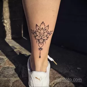 Фото тату: татуировка лотоса на икре, выполненная в технике dotwork с геометрическими элементами. Черно-белый рисунок, детализированный и изящный.