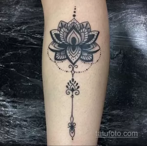 Фото тату: Черный тату лотоса на ноге, выполненный в стиле blackwork с геометрическими узорами и точками.