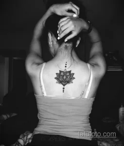 Фото тату: стильный лотос на шее, выполненный в технике blackwork. Татуировка состоит из плотных черных линий и геометрических узоров.