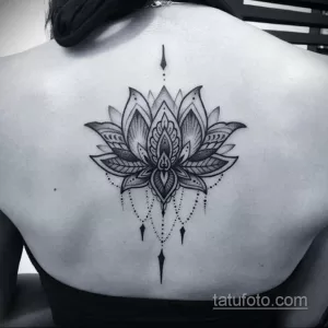 Фото тату: сложный геометрический рисунок цветка лотоса в стиле blackwork, расположенный на груди. Детализированные узоры и четкие линии.
