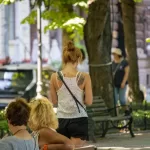 Фото тату на шее девушки: небольшой абстрактный цветочный рисунок, выполненный в черных тонах, с использованием тонких линий.