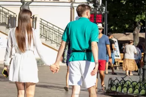 Фото тату на запястье мужчины, идущего с девушкой. Рисунок татуировки представляет собой абстрактный узор в минималистичном стиле.