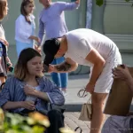 Фото мужчины с татуировкой на руке, смотрящего вниз. Видна часть рисунка татуировки в виде темных линий. Уличная фотография тату.