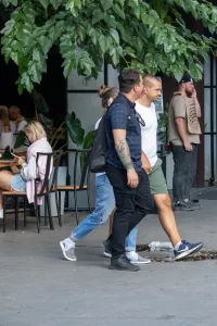 Фотография мужчины с татуировкой на предплечье, идущего по улице. Татуировка выполнена в ярких цветах и изображает череп с цветами.