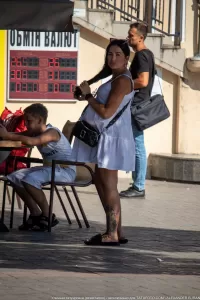 Фото тату: красивая роза с листьями на лодыжке женщины, выполненная в реалистичном стиле с использованием ярких цветов.