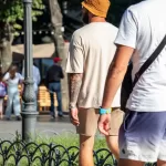 Фото тату на руке мужчины: реалистичный ворон с красными абстрактными мазками, выполненное в черных и красных тонах.
