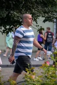 Фото тату на руке мужчины в полосатой футболке. Крупный план рукава татуировки с изображением дракона, черепа и цветов в японском стиле.