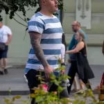 Фото тату на руке мужчины в полосатой футболке. Рукав татуировки с изображением дракона, черепа и цветов в японском стиле.
