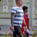 Фото тату на руке мужчины в полосатой футболке. Рукав татуировки с изображением дракона, черепа и цветов в японском стиле.