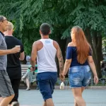 Фотография мужчины с татуировкой на руке, идущего по улице с девушкой.