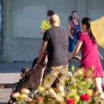 Фото татуировки на руке мужчины: темный рисунок, выполненный на предплечье. Изображение сделано на улице, в городской среде.