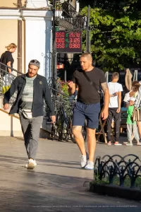Фото татуировки на руке мужчины, выполненной в геометрическом стиле. Рисунок состоит из черных кругов и орнаментов. На фоне городская улица.