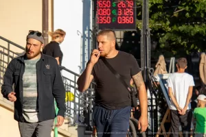 Фото тату на руке мужчины, идущего по улице. Татуировка выполнена в черных тонах, изображает геометрический узор. На фоне городская среда.