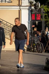 Фото тату на руке мужчины, стоящего на улице. Рисунок татуировки выполнен в стиле реализм, изображает сцену сражения или мифологического сюжета.