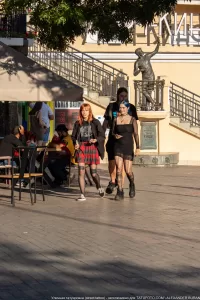 Фотография группы молодых людей, идущих по улице. У некоторых из них видны татуировки на руках и ногах, демонстрирующие различные стили и рисунки.