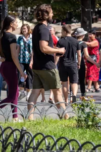 Фото мужчины с длинными волосами и бородой, на ногах которого видны татуировки с надписью и символами.