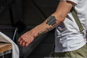 Фотография крупным планом татуировки с надписью "Freedom" и изображением здания на руке мужчины. Татуировка выполнена в черном цвете.