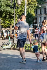 Фотография мужчины с татуировкой на руке, разговаривающего по телефону на улице. Татуировка выполнена черными чернилами в виде иероглифов.