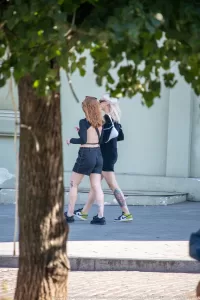 Фото ярких татуировок на ногах девушки: детализированные рисунки цветов, выполненные в насыщенных цветах, расположенные на икрах и бедрах.