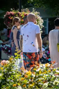 Фото татуировок на руках мужчины в летней одежде. Рукава украшены разноцветными брызгами краски и абстрактными рисунками.