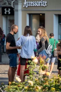 Фото девушки с татуировкой на руке, стоящей рядом с мужчиной. Рисунок татуировки выполнен в стиле реализм с черепом и цветами.