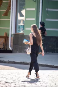 Фотография девушки, идущей по улице, с видимой татуировкой на плече. Татуировка выполнена в темных тонах и имеет сложный узор.