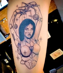 Фото тату на руке с изображением девушки, как куклы на нитях, с элементами космоса и символами. Стиль татуировки - графика с элементами реализма.