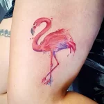 Фото акварельной татуировки фламинго на ноге. Мягкие розовые и фиолетовые оттенки создают романтичный и воздушный образ.