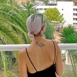 Фотография минималистичной татуировки на шее с изображением головы фламинго. Тонкие линии и лаконичный дизайн.