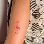 Фото тату маленького фламинго, выполненного в тонких красных линиях, как минималистичный рисунок на руке.