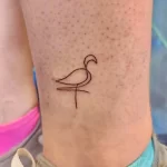 Фото минималистичной татуировки фламинго, выполненной одной непрерывной линией. Простой и элегантный дизайн, идеальный для любителей лаконичности.