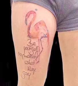 Фото тату фламинго, выполненного в акварельной технике, с надписью "Be yourself no matter what they say".