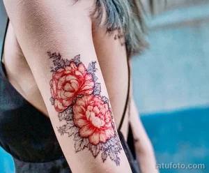 Фото тату: цветная татуировка с изображением двух распустившихся пионов на плече. Красный и синий цвета создают контрастный и эффектный рисунок.