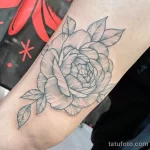 Фото тату: небольшая татуировка пиона в стиле blackwork на руке, тонкие линии, минимализм, черно-белый рисунок, элегантный дизайн.