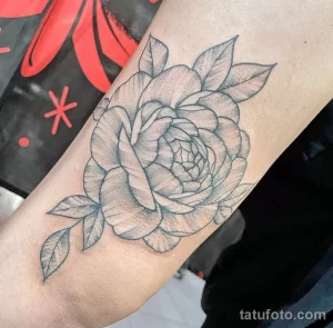 Фото тату: небольшая татуировка пиона в стиле blackwork на руке, тонкие линии, минимализм, черно-белый рисунок, элегантный дизайн.