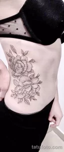 Фото татуировки пионов на женском боку, выполненной в технике blackwork с использованием тонких линий и точечной штриховки.