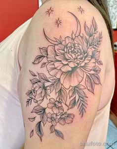 Фото татуировки пионов, луны и звезд на плече. Рисунок выполнен в технике blackwork с использованием тонких линий и точечной штриховки.