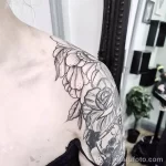 Фото тату: оригинальная татуировка на плече, сочетающая нежные пионы и мрачный череп. Черно-белый рисунок с высокой детализацией и контрастными элементами.