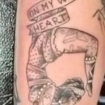 Фото татуировки гимнастки с надписью "Blame it on my wild heart" на руке. Черно-серый рисунок в стиле sketch.