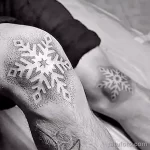 Фото татуировки крупной снежинки в технике blackwork на руке. Плотное заполнение черным цветом и четкие линии.