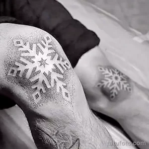 Фото татуировки крупной снежинки в технике blackwork на руке. Плотное заполнение черным цветом и четкие линии.